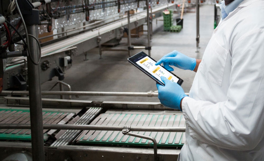 Person using tablet with Hx Manager controlling Hx Nitro thermal inkjet printer in the production line